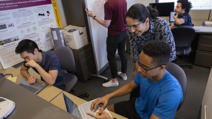 Professor helps a student working on a laptop.