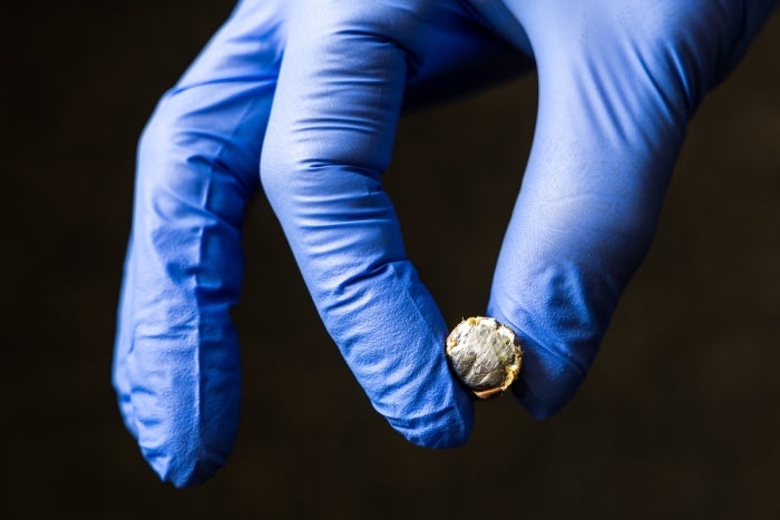 Two gloved fingers holding a bullet