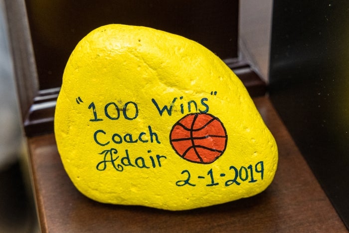 Painted rock that says "100 Wins Coach Adair 2-1-2019"