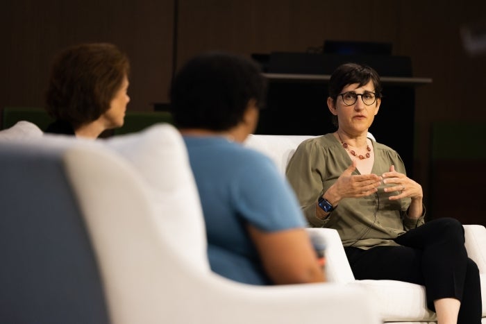 3 women sit in chairs in front of a crowd