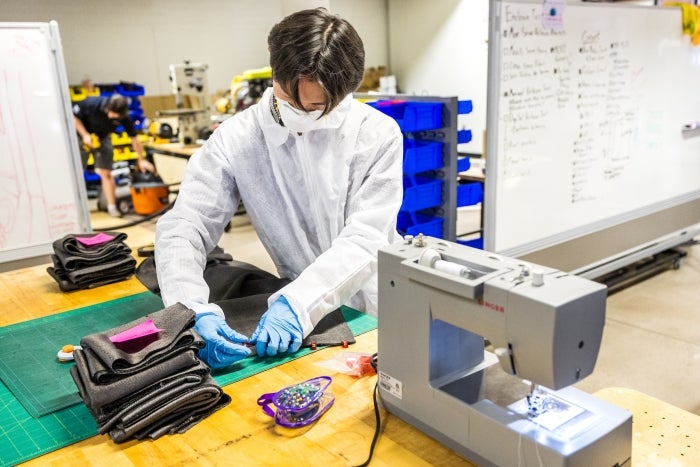 Student wearing clean room protective gear pins fabric in a lab