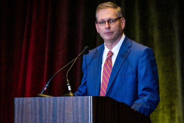 Man in a suit and tie talks at a lectern