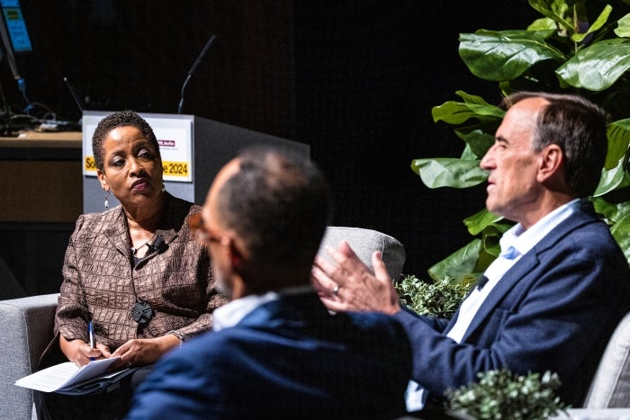 Woman moderating panel looks on as man on panel answers question