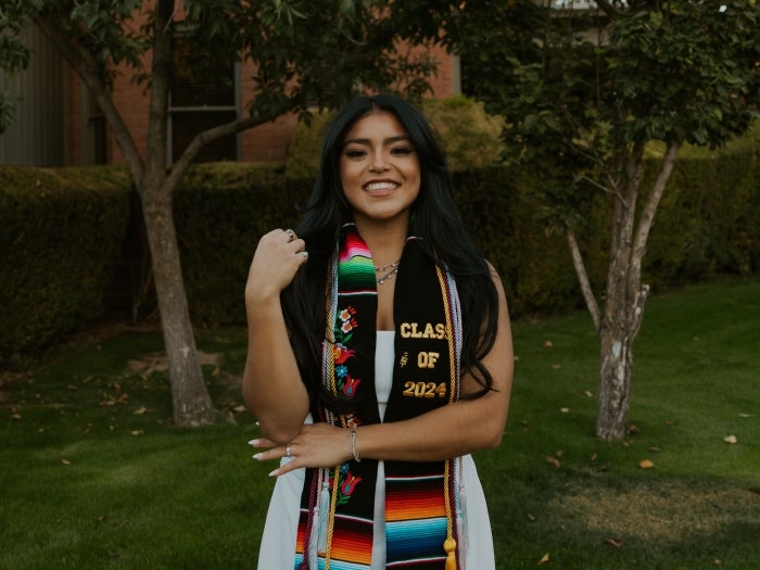 Image of SST Dean's Medalist, Felicity Miranda, smiling at the camera with her graduation stoles 