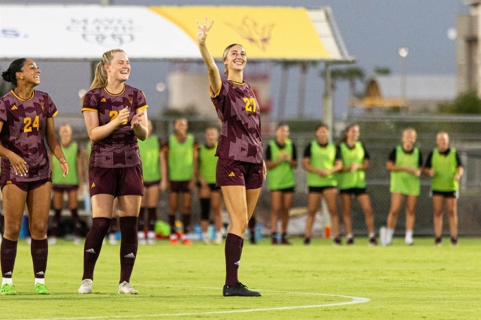 Lauren Kirberg stands on a soccer field and waves.