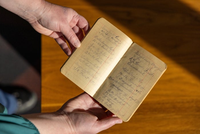 Hands holding a small ledger with handwritten notes