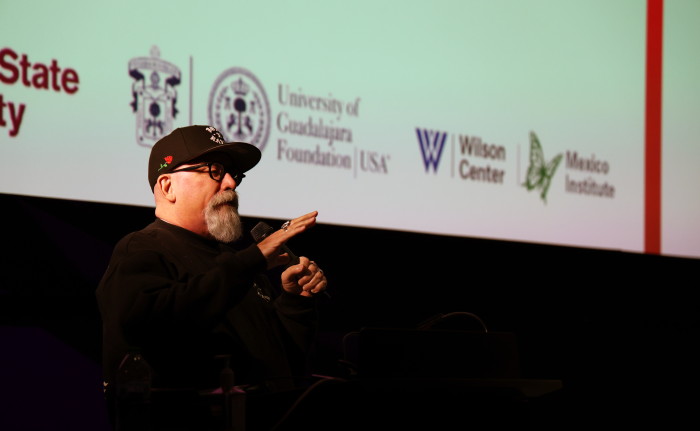 A man speaks into a microphone on stage. 