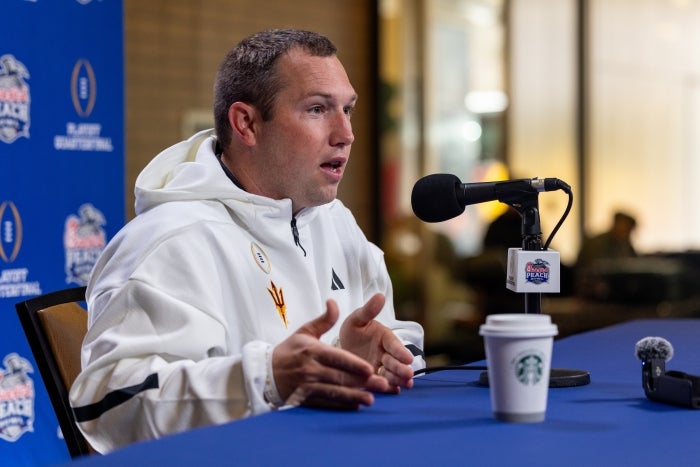 ASU football coach Kenny Dillingham speaks into a mic at a table