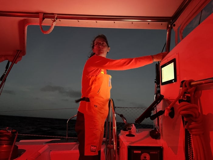 Julia Tizard Hunter standing at a boat's helm with a glowing red screen at night.