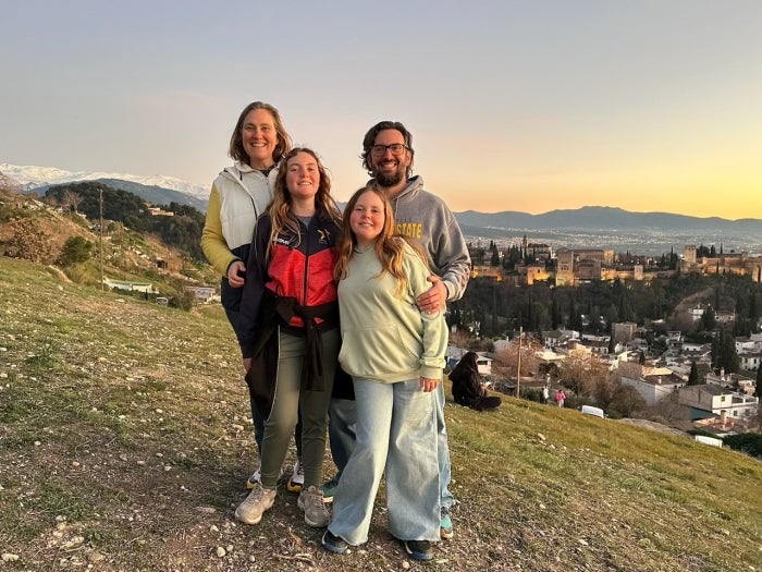 A family stands on a hill top at sunset