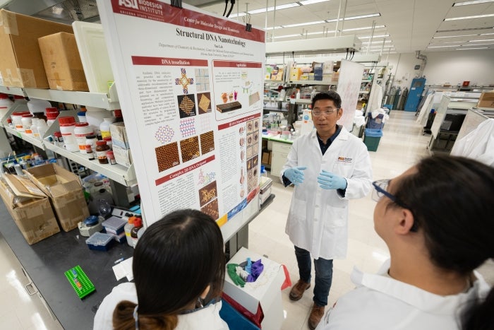 People in white lab coats standing around talking in lab