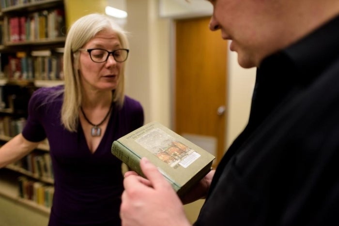 Two people discuss a book with bookcases behind them. Photo by Andy DeLisle/ASU.