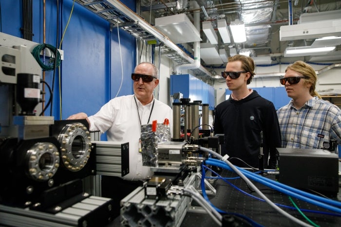 Mark Holl (left), Gavin Russo (middle) and Albert Richardson (right) examine the setup in the experimental sample chamber hutch. 