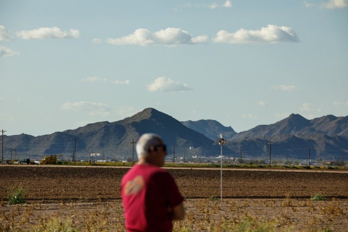 Scott in blurred foreground and dirt field and mountains in focus in background