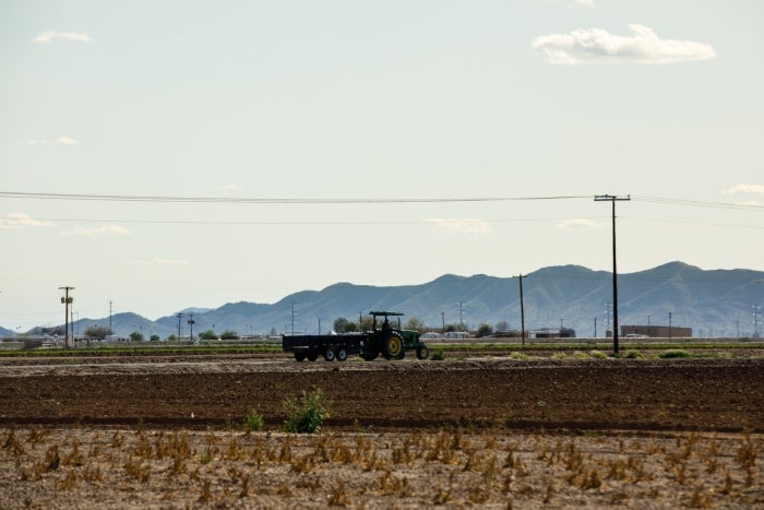 tractor driving over a field with mountains in the distance