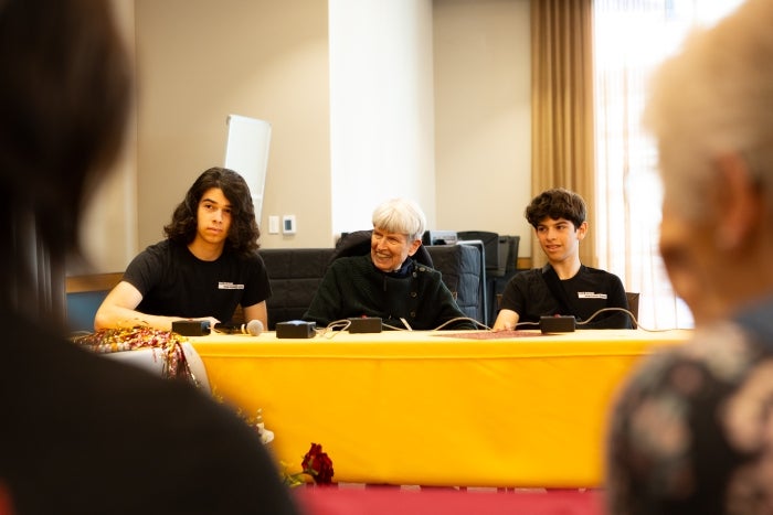 Grandsons sit with their grandmother during a quiz bowl event.