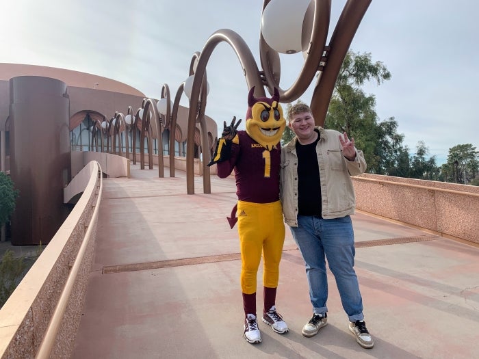 Student posing with Sparky on ASU Gammage bridge