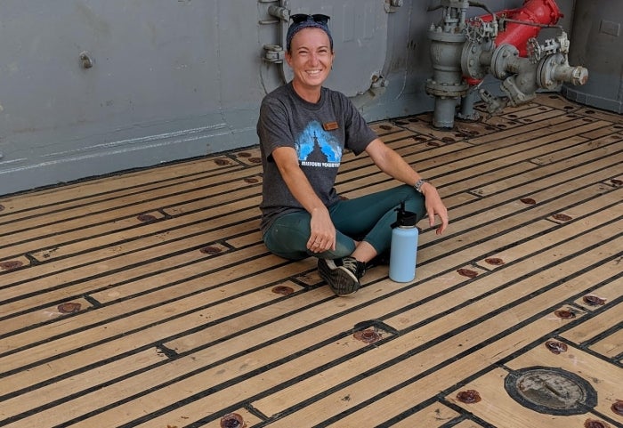 Woman sitting cross-legged on the ground.