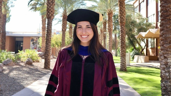 Woman posing in cap and gown on Palm Walk