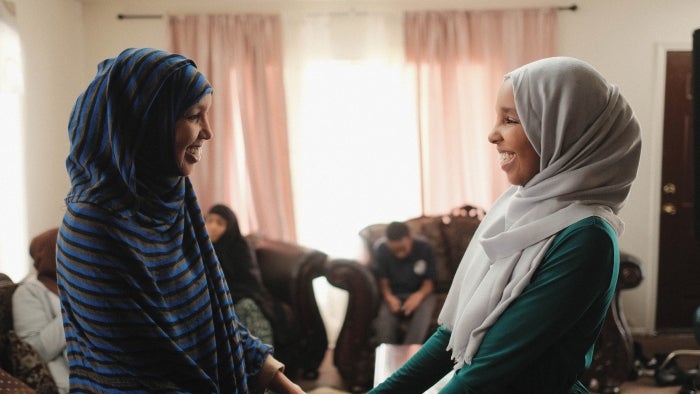 A mother and daughter hold hands and smile at each other