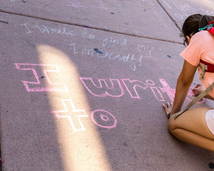 A student uses sidewalk chalk to write during ASU's celebration of the National Day on Writing in 2019. Photo by Bruce Matsunaga / ASU.