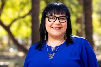 A woman in a blue blouse smiles for the camera. 