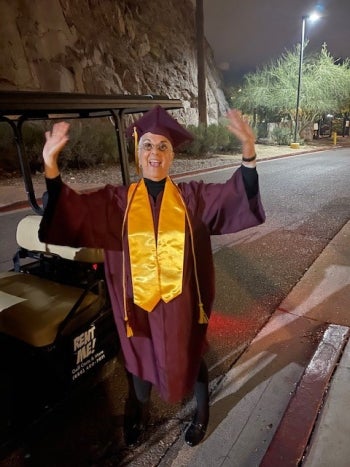 Woman in cap and gown with arms raised in air