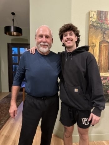 An older and younger man standing side by side smiling