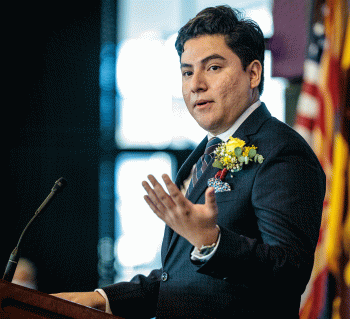 A man in a suit speaks at a lectern