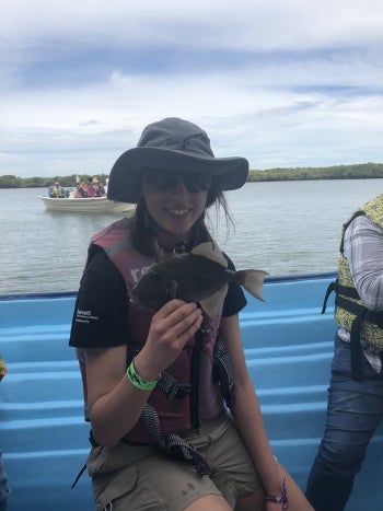 Woman in a boat holding a fish.