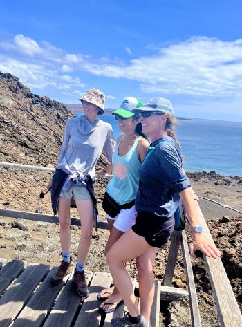 Three people pose for a photo at an overlook in a mountainous environment.