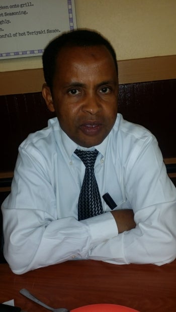 Man in a white collared shirt and dark tie sitting at a table