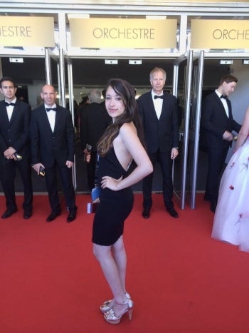 Woman in a black dress posing on a red carpet.