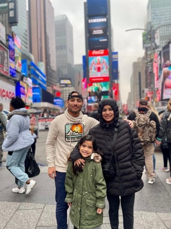 Man, woman and child smile in Times Square.