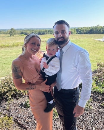 Dawson Hendricks stands with his wife as she holds their son outside.