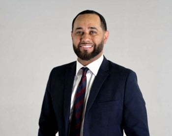 Photo of Dimitri Hurt wearing a suit and tie in front of a white background