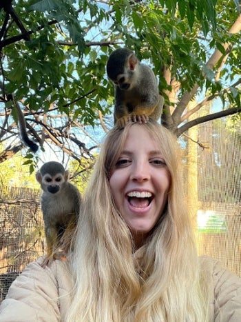 Megan Larsen smiling in South Africa with monkeys on her head and shoulder