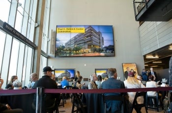 People gathered at an event in front of a large screen.