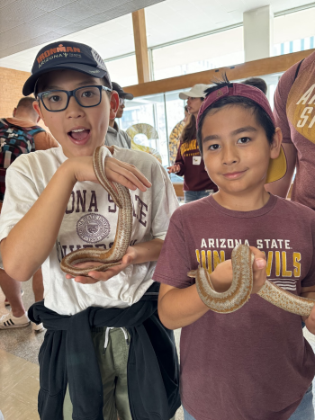 Two kids holding snakes at ASU event