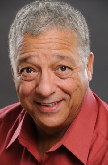 Portrait of older man with short salt and pepper hair wearing a collared red shirt