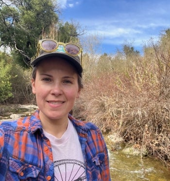 Headshot of Tamara Harms out in the field, wearing a plaid shirt with a baseball cap and sunglasses.