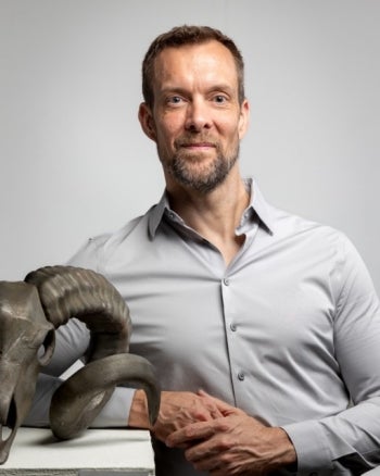 Bruce Ward stands next to a cast of a ram skull.