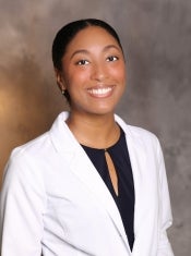 ASU Nursing Alumna Davina Vea smiles at the camera she is wearing a white blazer and black blouse.