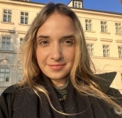 A smiling woman in front of a tall building.