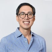 ASU directory photo of new faculty member Christian Ravela, who wears glasses and a blue checked shirt and poses in front of a light grey background.