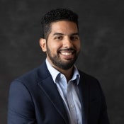 Courtesy photo of ASU professor Eduardo Ramos, who has dark hair and a beard and stands in front of a dark grey background wearing a blue suit.