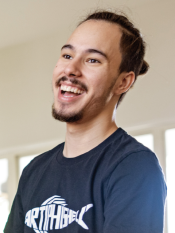 Portrait of a young man in a black t-shirt with pulled up dark hair and a goatee