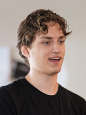 Portrait of a young man with short brown hair wearing a black t-shirt