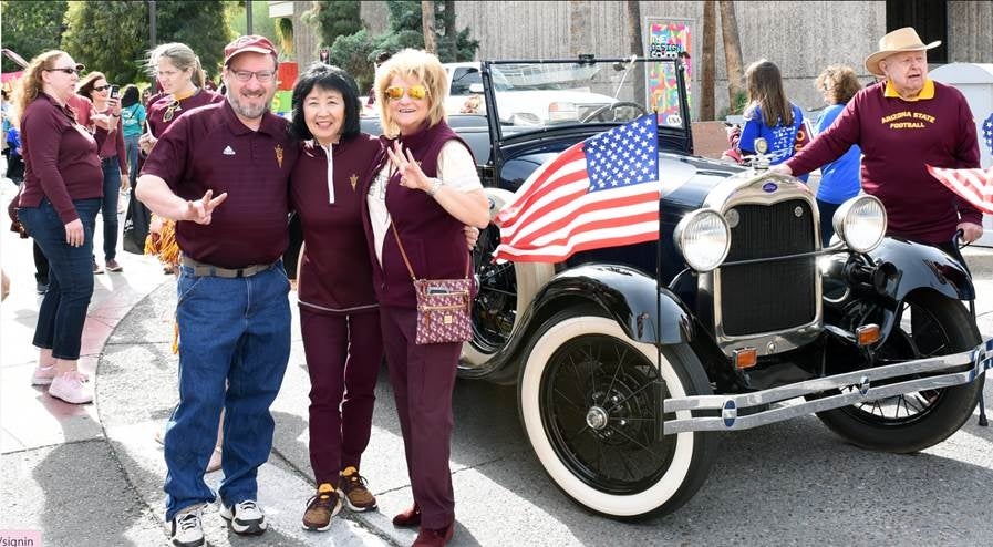 People standing next to an old car making the ASU pitchfork symbol.