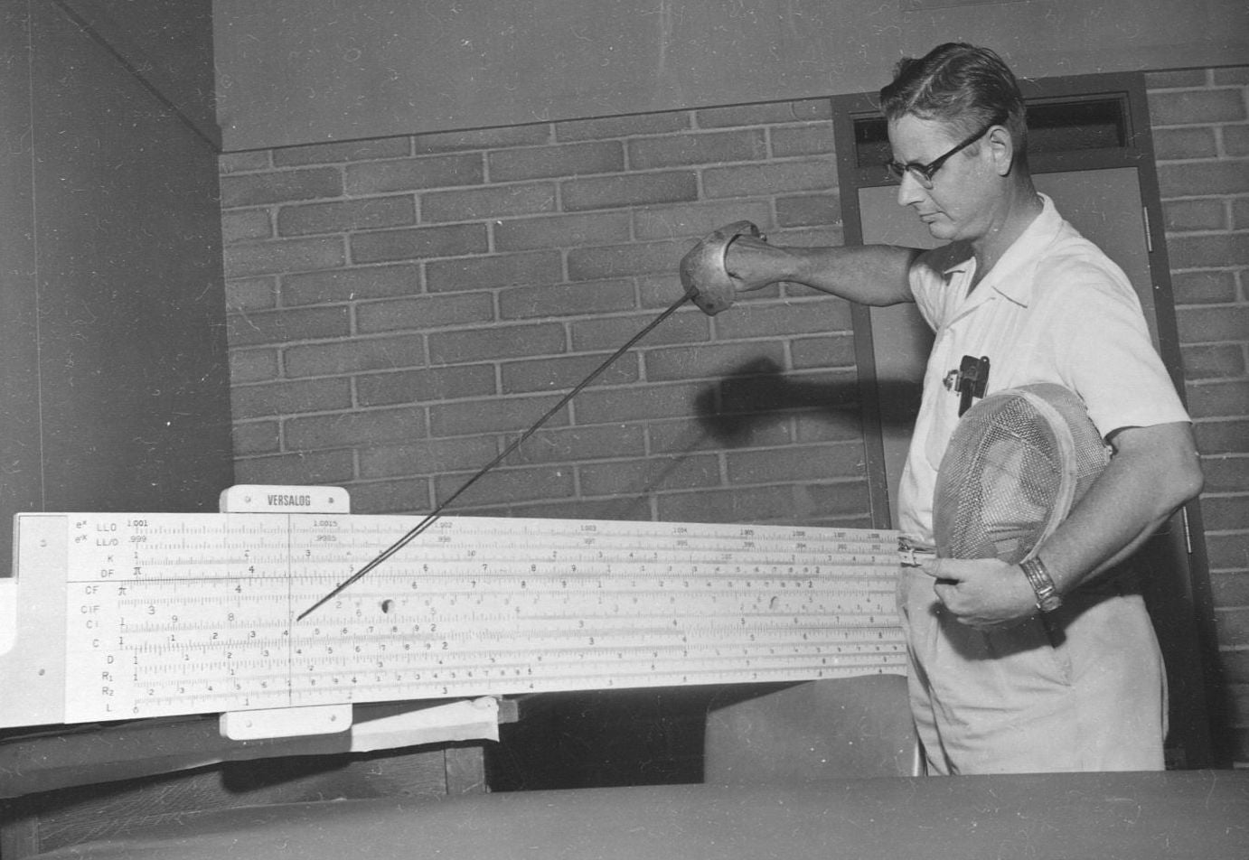 George Beakley Jr. with giant slide rule and fencing sword